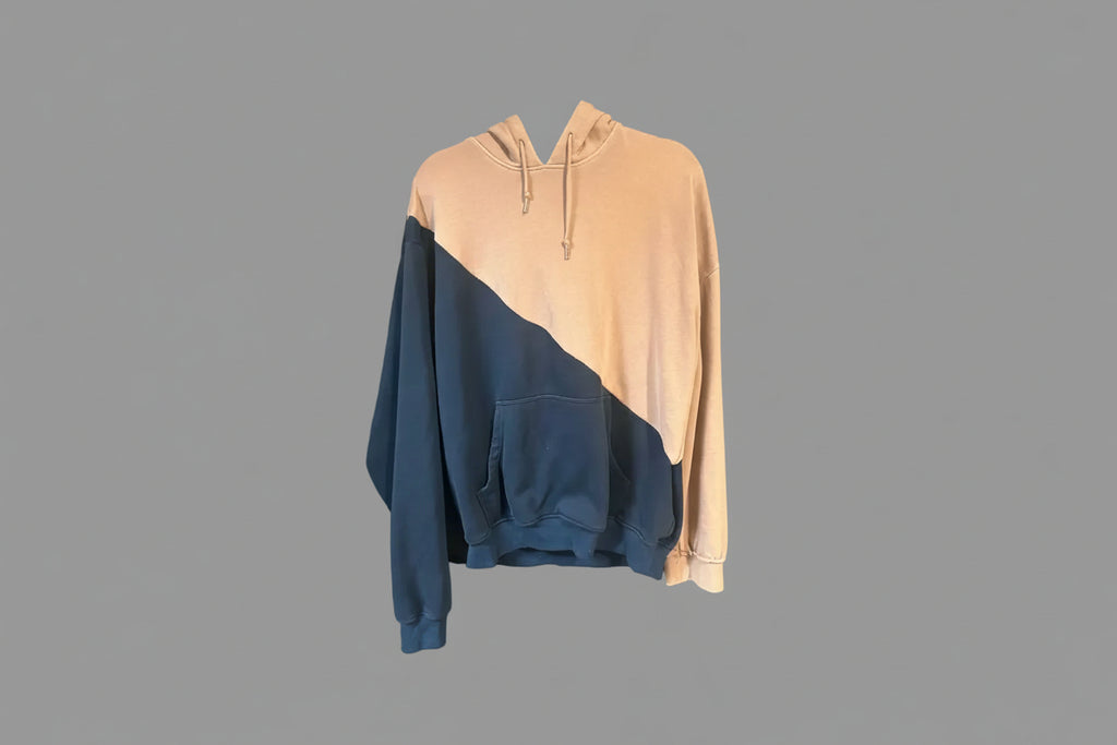 Two-tone hoodie with beige top and blue bottom on a gray surface
