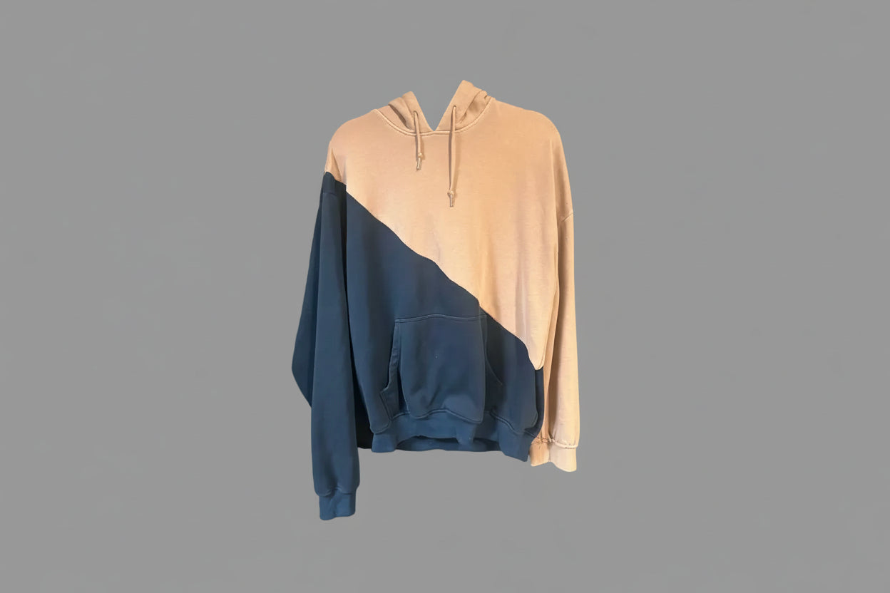 Two-tone hoodie with beige top and blue bottom on a gray surface